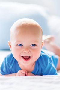 smiling Baby on stomach | Contact Pediatric Physical Therapy
