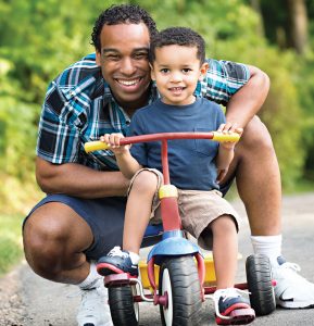 African American father and boy toddler (on a tricycle)