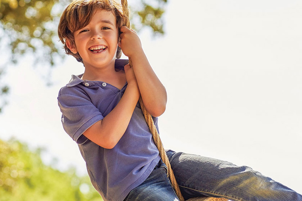 young smiling boy on a rope swing