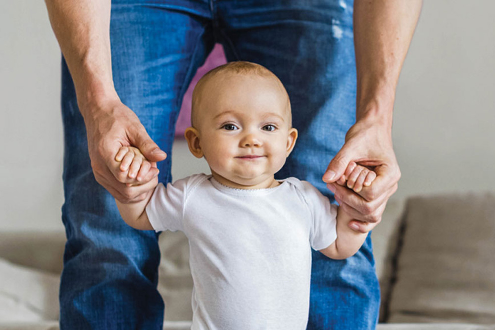 Infant being held up by the arms by his dad